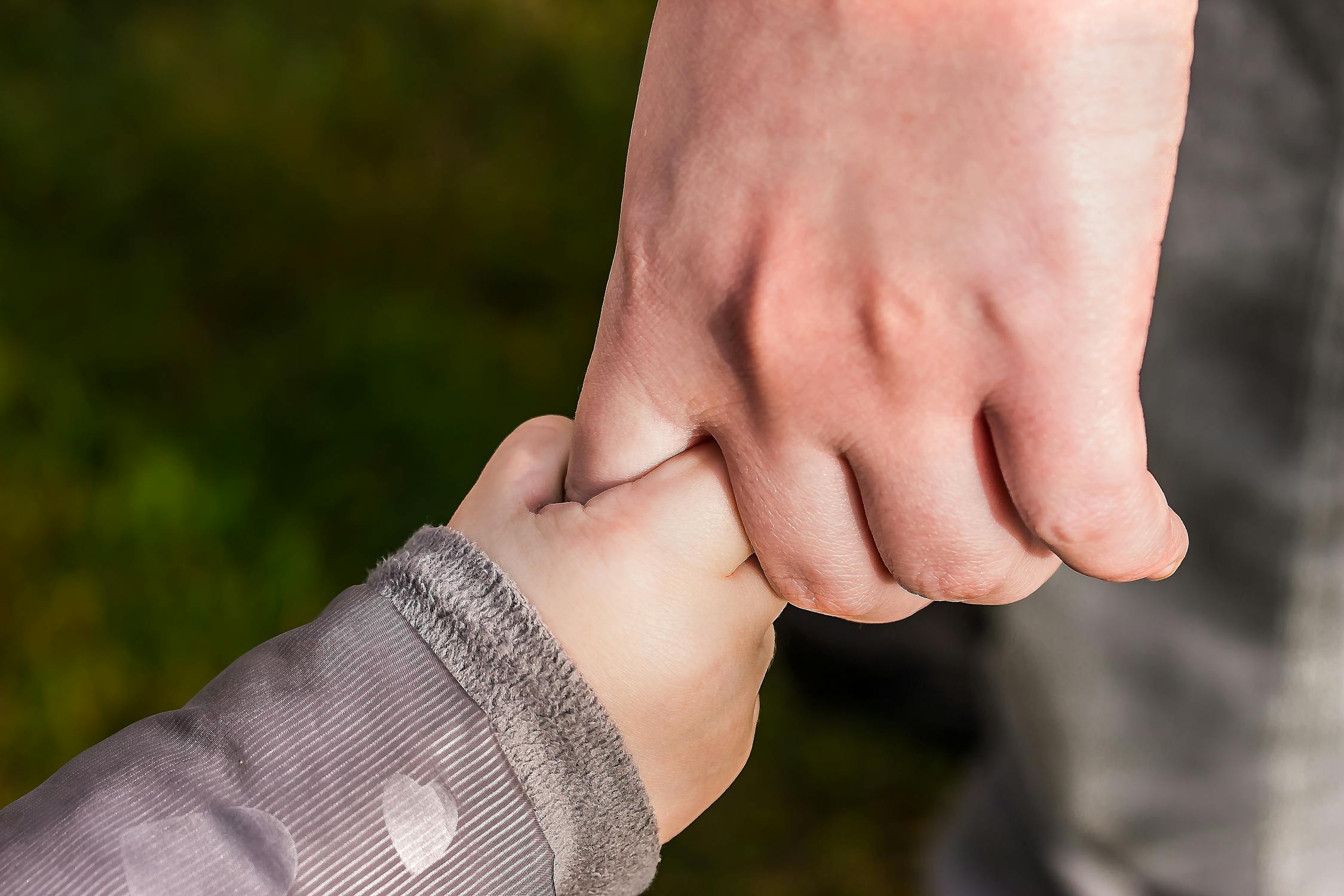 hands little hand holding a big hand with a green background